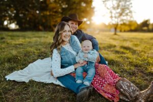 man woman and child sitting on the grass
