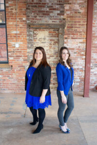 two women in blue standing back to back