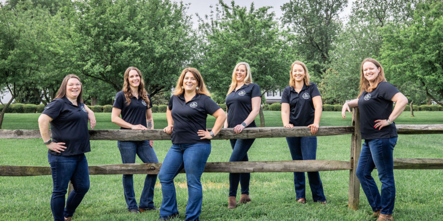 6 women standing by fence