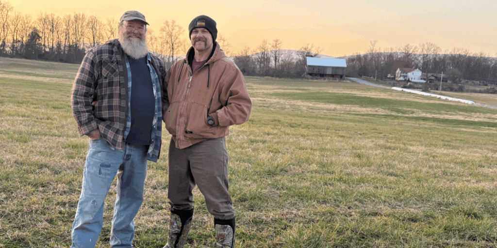two men standing in a farm field