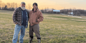 two men standing in a farm field