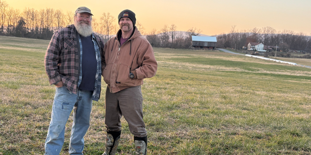 two men standing in a farm field