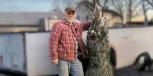 A man standing in front of a truck with a Christmas tree.