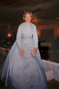 A women standing in a blue 70s style ball gown 