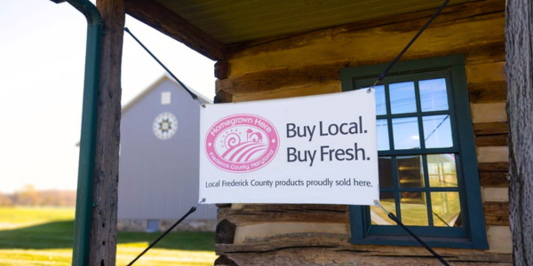 a sign in front of a log cabin that says buy local. Buy fresh.
