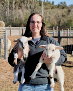 a women holding two goats