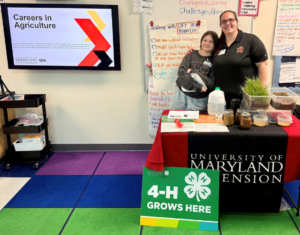 two people standing in a classroom behind a booth