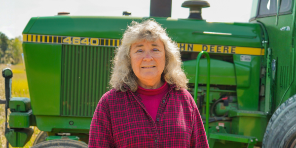 a women smiling in front of a green tractor